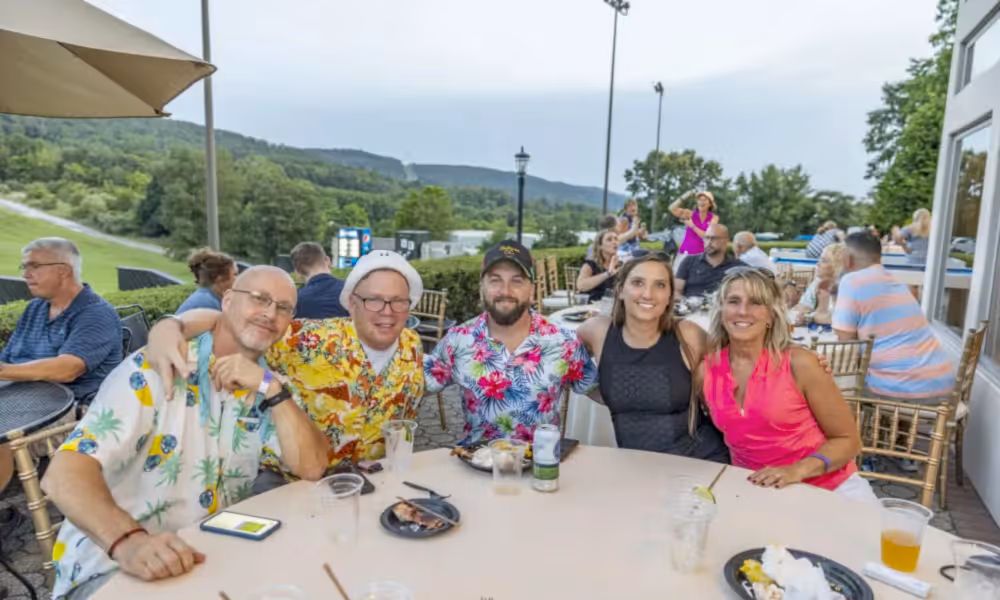 Group of people sitting at table with mountain view behind them.